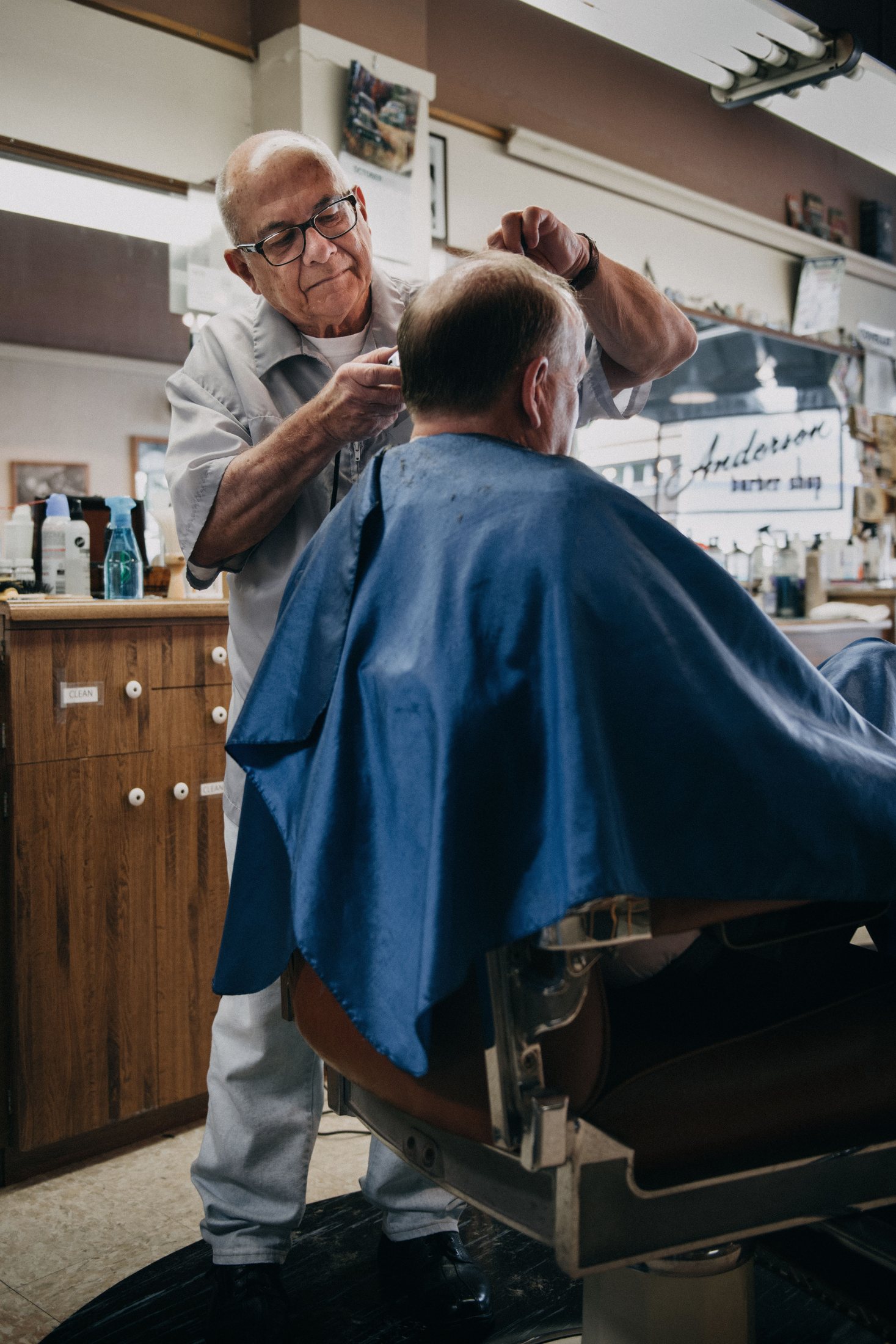 Barbeiro realizando corte de cabelo em barbearia